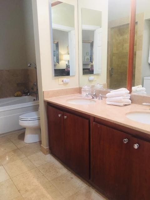 full bathroom with a bathtub, double vanity, toilet, and a sink