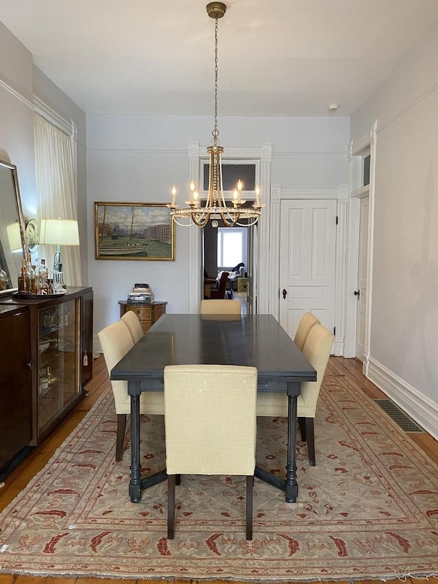 dining room with visible vents, baseboards, an inviting chandelier, and wood finished floors