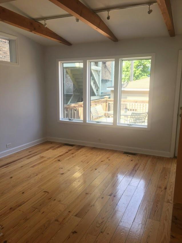 empty room with lofted ceiling with beams, rail lighting, baseboards, and light wood finished floors