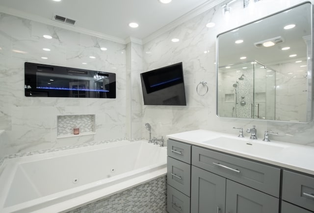 bathroom featuring tile walls, vanity, visible vents, a jetted tub, and crown molding