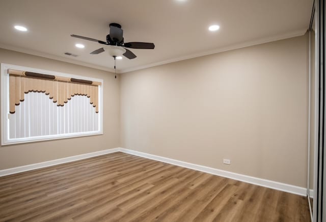 spare room with ornamental molding, wood finished floors, visible vents, and baseboards