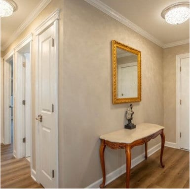 corridor with crown molding, baseboards, and wood finished floors