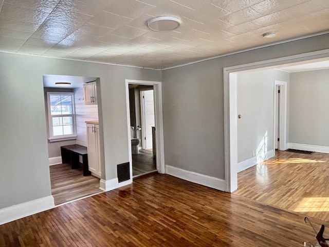 unfurnished bedroom with wood finished floors, visible vents, and baseboards