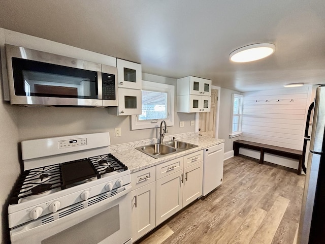 kitchen with glass insert cabinets, white cabinetry, a sink, and appliances with stainless steel finishes