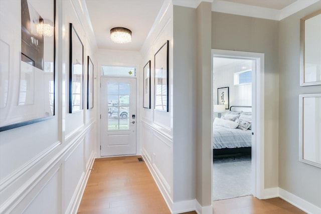 doorway with ornamental molding and light hardwood / wood-style flooring