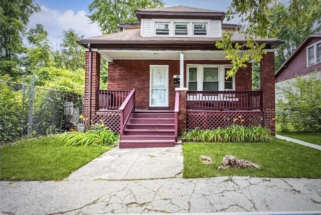 bungalow-style home with covered porch, a front yard, fence, and brick siding