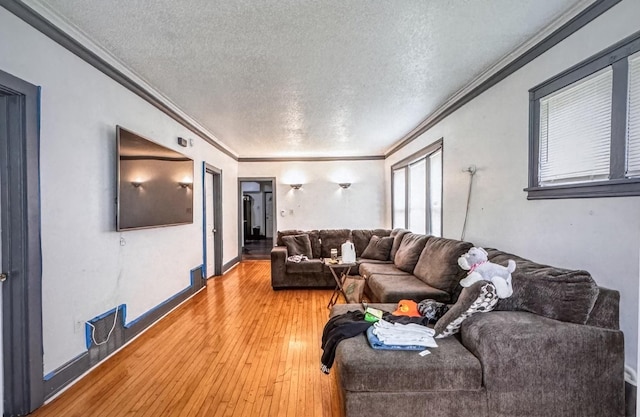 living room with a textured ceiling, baseboards, wood finished floors, and crown molding