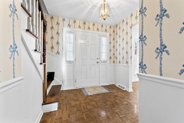 entryway featuring stairway, wainscoting, visible vents, and wallpapered walls