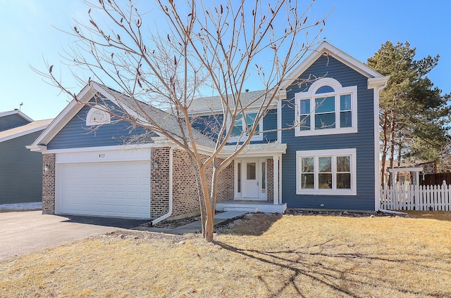 traditional-style home with a garage, driveway, and fence