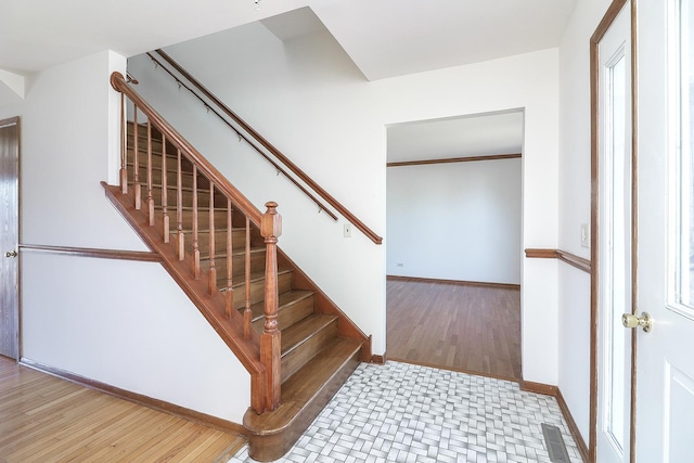 stairway with wood finished floors, visible vents, and baseboards