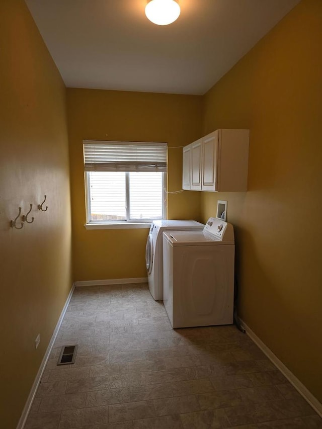 clothes washing area featuring independent washer and dryer and cabinets