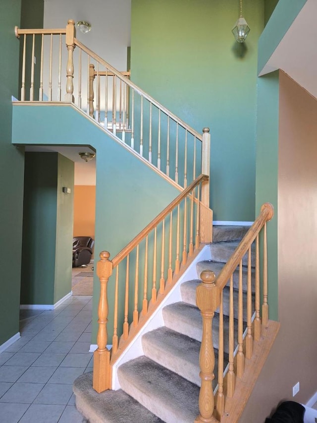 staircase with tile patterned floors and a high ceiling