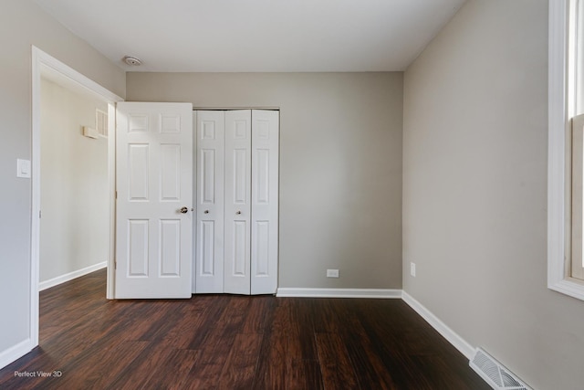 unfurnished bedroom with a closet and dark hardwood / wood-style floors