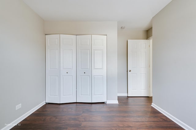 unfurnished bedroom with dark hardwood / wood-style flooring and a closet