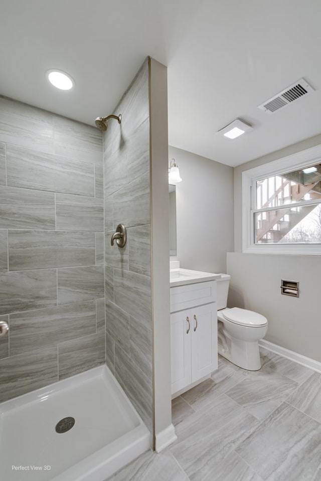 bathroom with vanity, tiled shower, and toilet