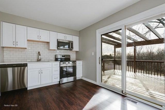 kitchen with white cabinetry, stainless steel appliances, backsplash, and sink