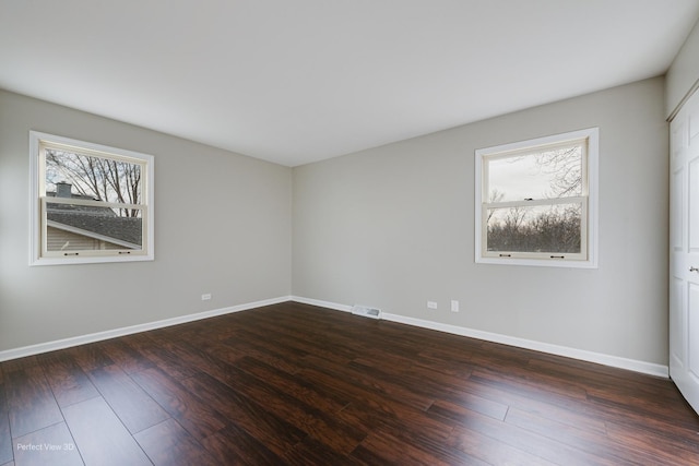 spare room with plenty of natural light and dark hardwood / wood-style floors