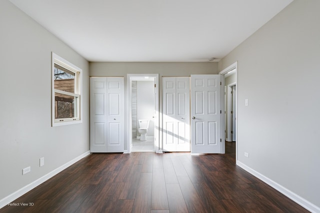 unfurnished bedroom featuring dark hardwood / wood-style floors and connected bathroom