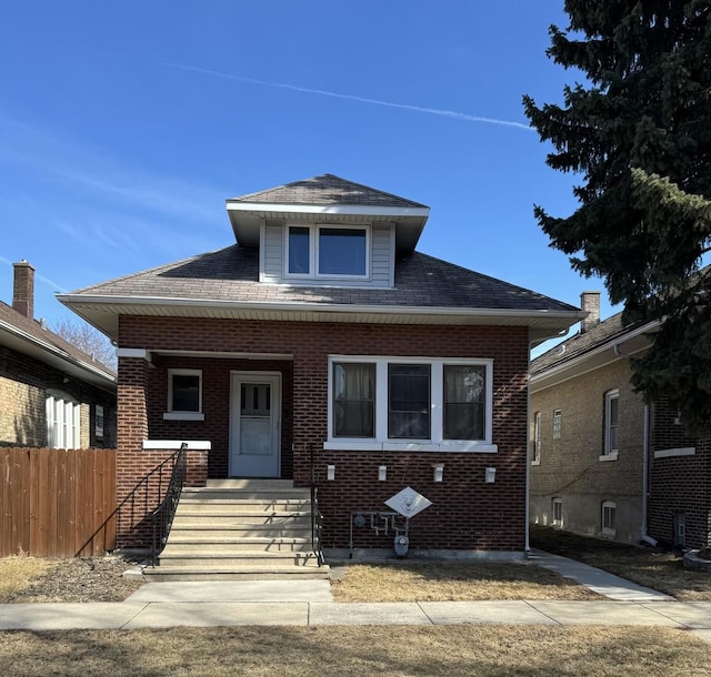 bungalow featuring a porch, brick siding, fence, and a shingled roof