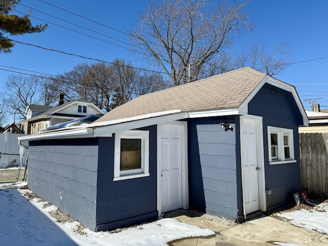 snow covered structure with an outbuilding and fence