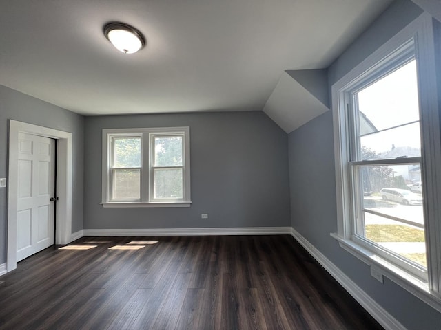 bonus room with dark wood-type flooring, a healthy amount of sunlight, and baseboards