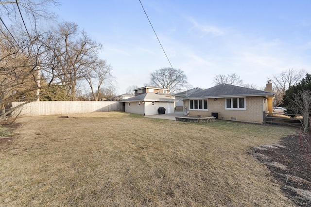 rear view of house featuring a yard, a chimney, a patio area, brick siding, and a fenced backyard