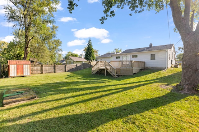 view of yard featuring an outbuilding, a fenced backyard, stairs, a wooden deck, and a shed