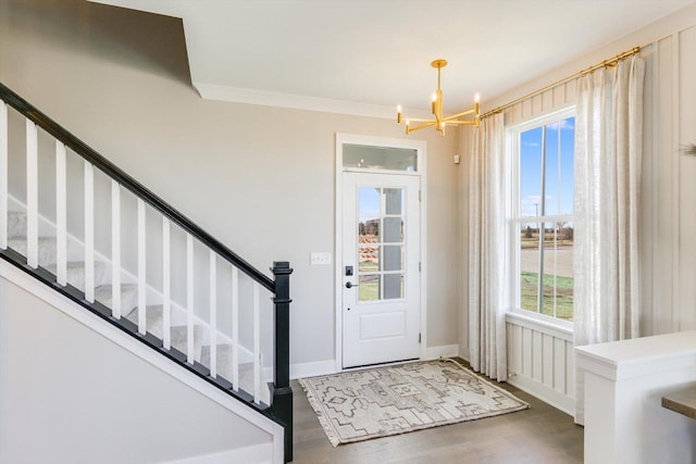 foyer entrance featuring ornamental molding, dark wood-type flooring, and a notable chandelier