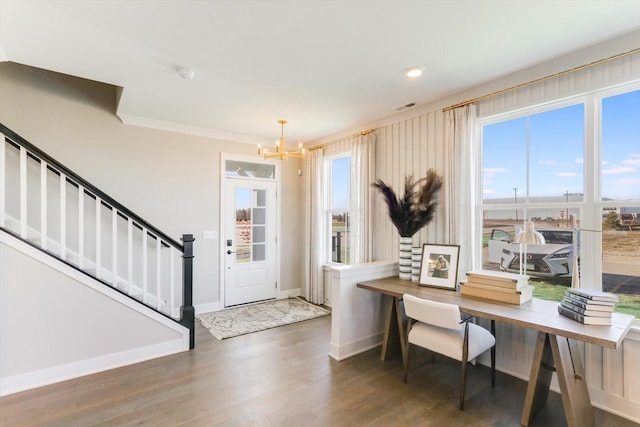 foyer with ornamental molding, an inviting chandelier, dark hardwood / wood-style floors, and plenty of natural light