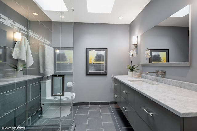 full bathroom featuring a skylight, baseboards, toilet, tile patterned flooring, and vanity