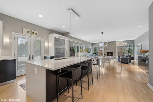 kitchen with pendant lighting, french doors, a spacious island, light countertops, and stainless steel built in refrigerator