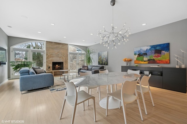 dining space with a large fireplace, recessed lighting, and light wood-style floors