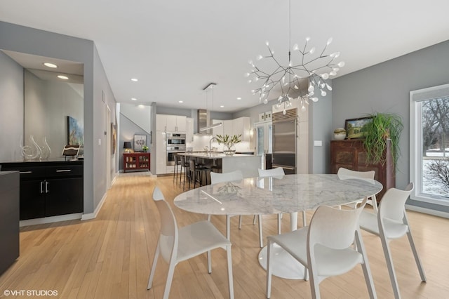 dining space featuring light wood-type flooring, an inviting chandelier, baseboards, and recessed lighting