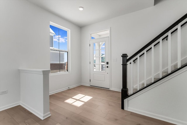 entryway with stairway, light wood-type flooring, and baseboards