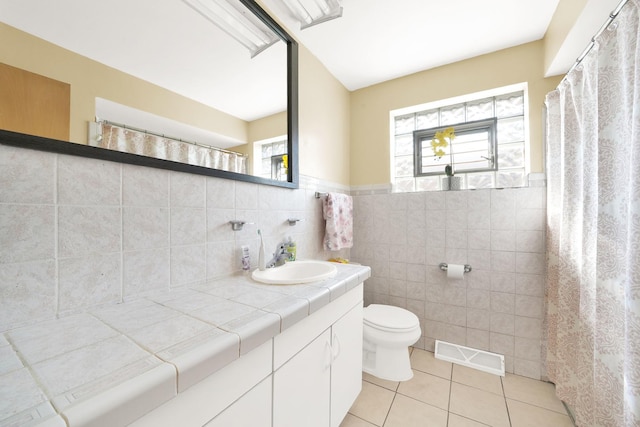 bathroom featuring a wealth of natural light, tile walls, tile patterned flooring, and vanity