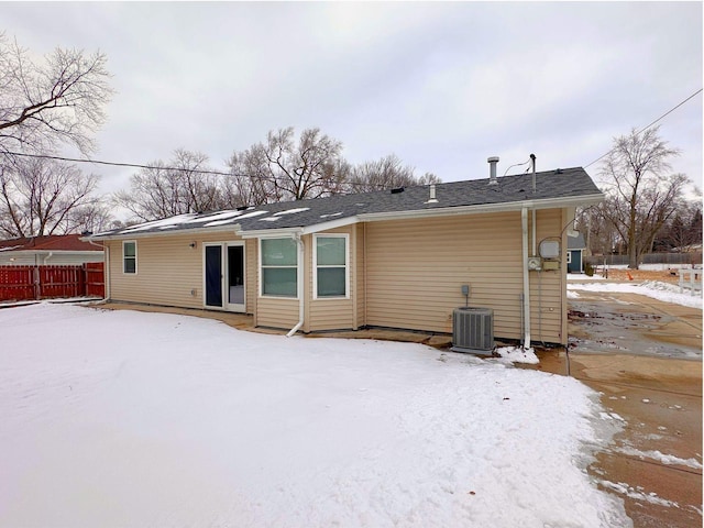 snow covered rear of property featuring fence and cooling unit