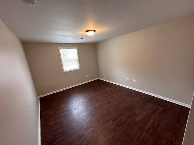 empty room with dark wood-style flooring and baseboards