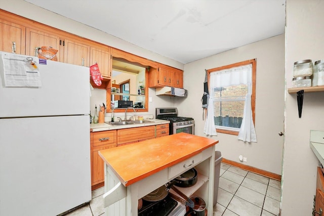 kitchen with gas stove, butcher block countertops, sink, white fridge, and light tile patterned floors