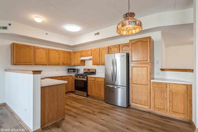 kitchen with visible vents, dark wood-type flooring, hanging light fixtures, stainless steel appliances, and under cabinet range hood