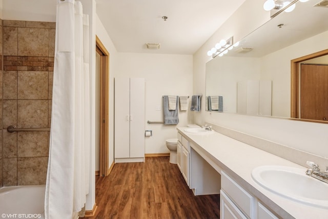 full bathroom featuring double vanity, visible vents, toilet, a sink, and wood finished floors