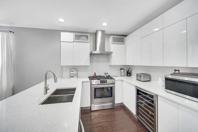 kitchen featuring beverage cooler, stainless steel appliances, modern cabinets, wall chimney exhaust hood, and a sink