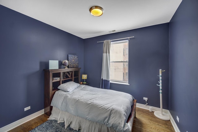 bedroom with visible vents, baseboards, and wood finished floors