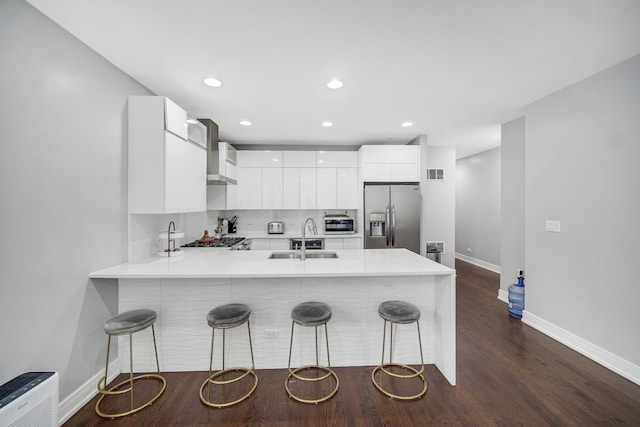 kitchen featuring a breakfast bar, a peninsula, stainless steel appliances, white cabinetry, and modern cabinets