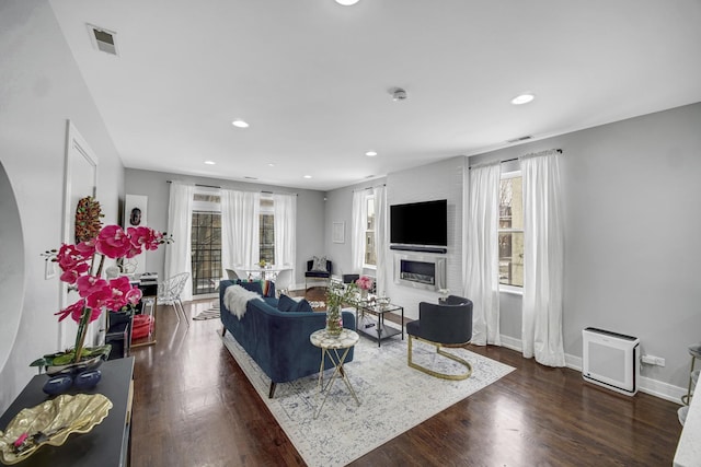 living area with visible vents, wood finished floors, recessed lighting, a large fireplace, and baseboards