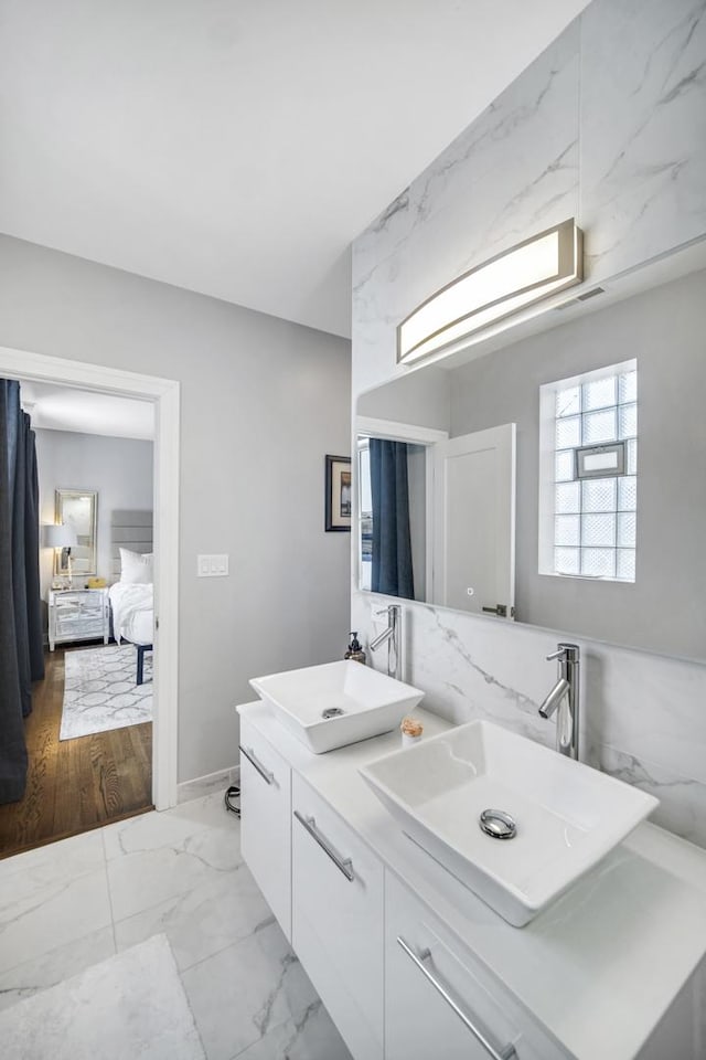 bathroom featuring ensuite bath, double vanity, marble finish floor, and a sink