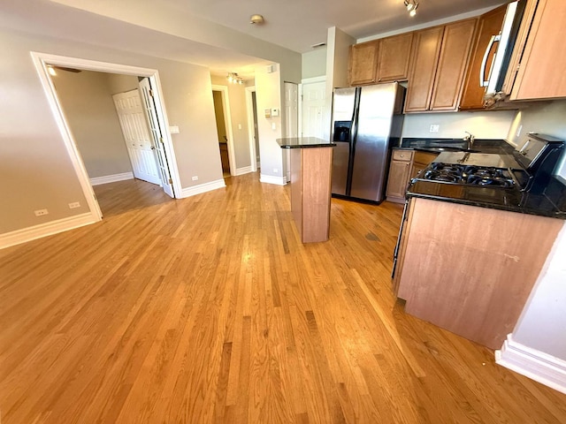 kitchen with dark countertops, light wood-style flooring, a kitchen island, and stainless steel fridge with ice dispenser