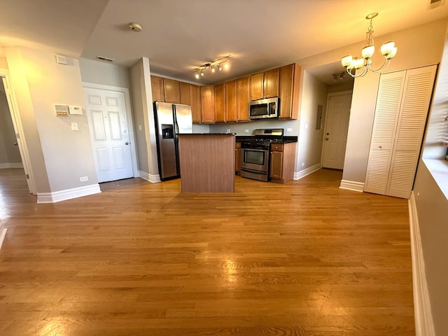 kitchen featuring a center island, stainless steel appliances, dark countertops, hanging light fixtures, and open floor plan