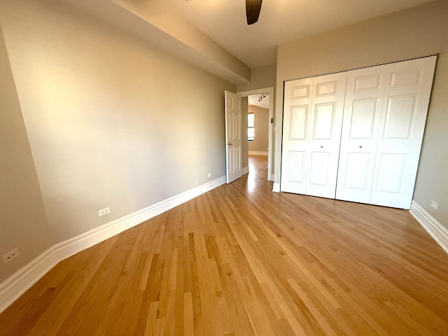 unfurnished bedroom featuring light wood-style floors, a closet, ceiling fan, and baseboards