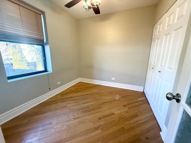 unfurnished bedroom featuring a closet, ceiling fan, baseboards, and wood finished floors