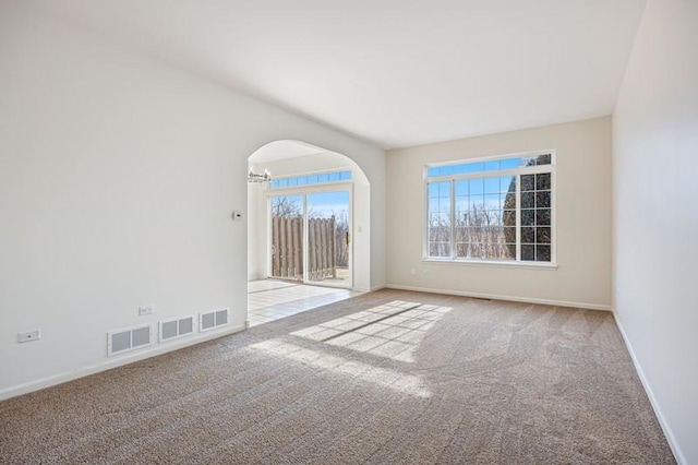 carpeted empty room with an inviting chandelier